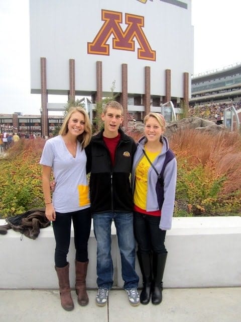 three people standing in front of the minnesota golden gophers stadium.