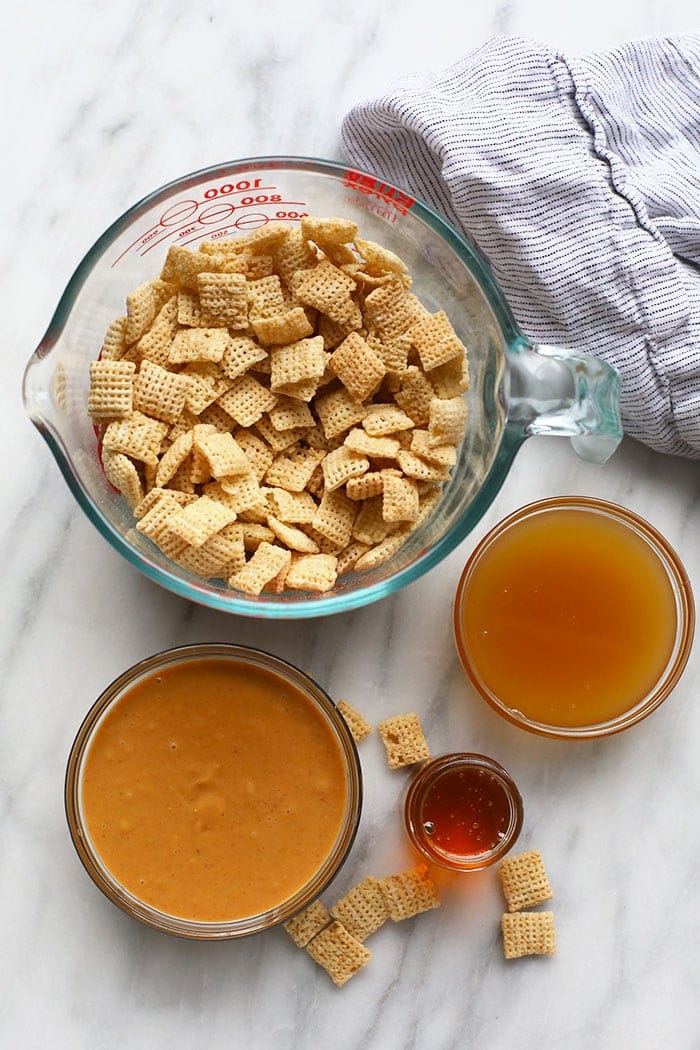 A bowl of cheesy granola, a bowl of honey, and a bowl of ketchup.