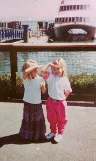 two little girls standing in front of a boat.