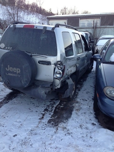 a silver jeep parked in a snowy lot.