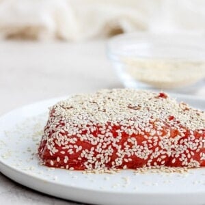 a piece of seared ahi tuna with sesame seeds on a plate.