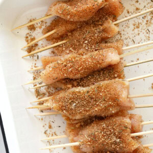 Chicken skewers arranged in a baking dish.