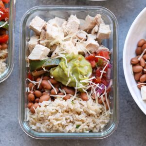 Save your money and make your own affordable Copycat Chipotle Chicken Burrito Bowls at home! These healthy chicken burrito bowls are made just like the real thing made with baked chicken, cilantro lime brown rice, beans, and fajita veggies, and your favorite toppings!