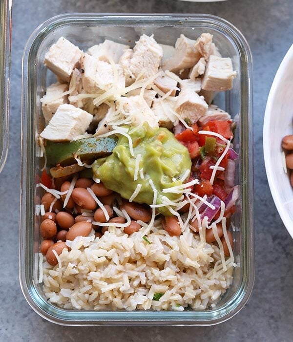 Save your money and make your own affordable Copycat Chipotle Chicken Burrito Bowls at home! These healthy chicken burrito bowls are made just like the real thing made with baked chicken, cilantro lime brown rice, beans, and fajita veggies, and your favorite toppings!