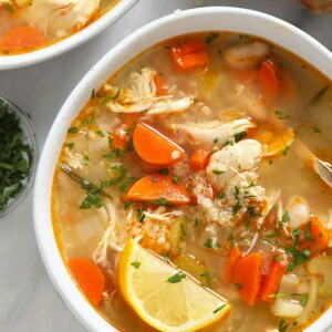 two bowls of chicken soup on a marble table.