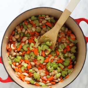 A hearty chicken soup packed with nutritious vegetables, quinoa, and beans, served on a stylish marble countertop.