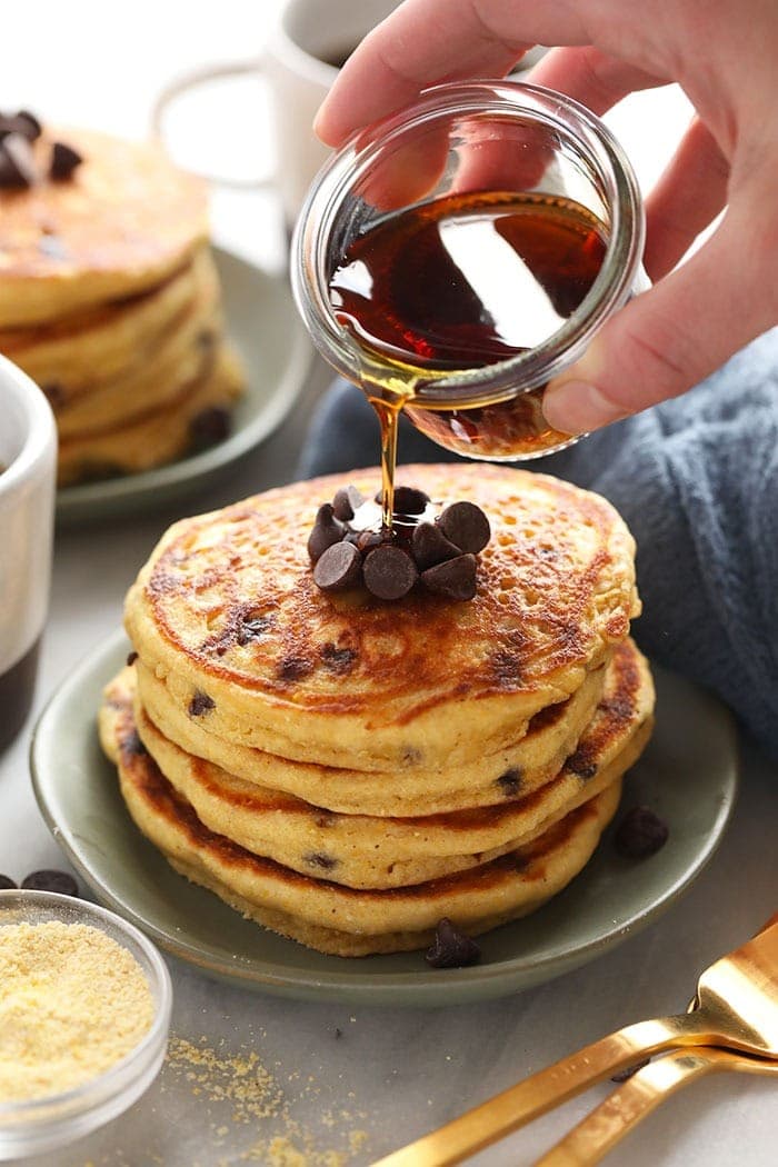 pouring maple syrup onto pancakes