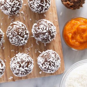 chocolate coconut energy balls on a cutting board alongside pumpkin gingerbread energy balls.