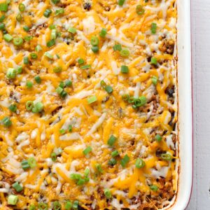 a chicken casserole topped with cheese and green onions.