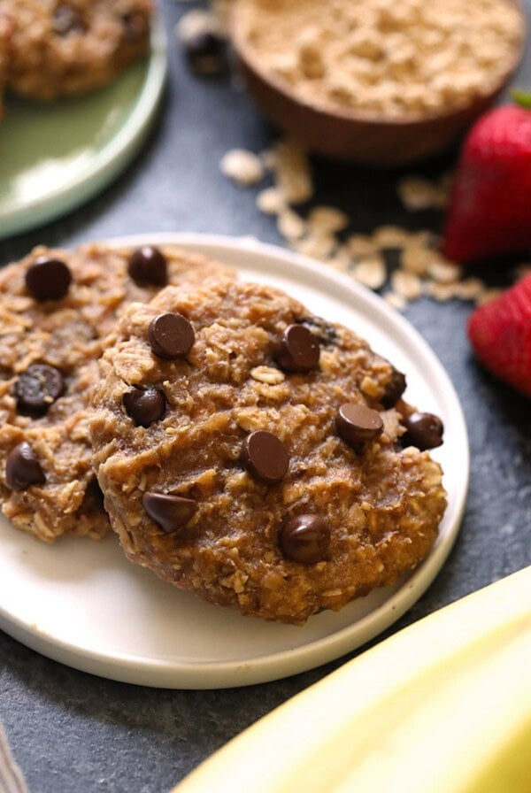 Vegan banana chocolate chip cookies on a plate with strawberries and bananas.