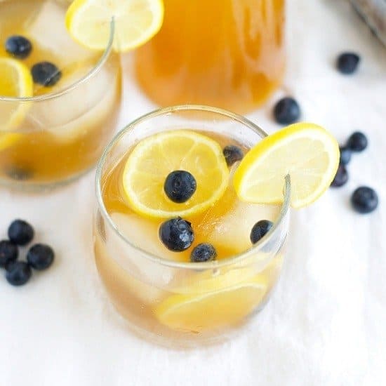 Two glasses of lemonade with blueberries, ice, and a twist of kombucha.