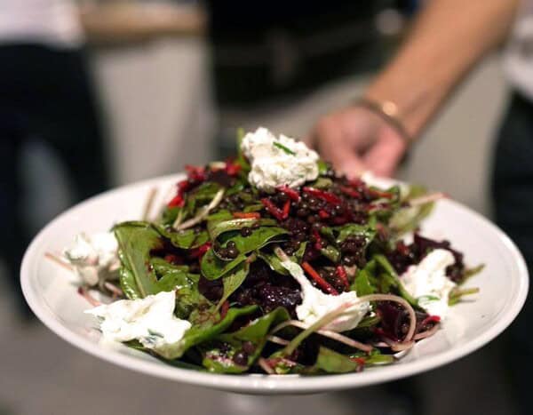 a person is holding a white plate with a salad on it.