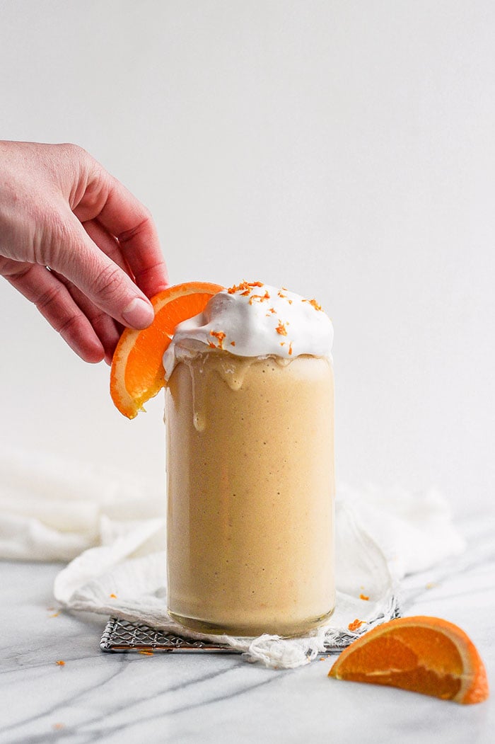 orange creamsicle smoothie with hand on orange slice