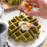 A person is pouring honey on matcha waffles.