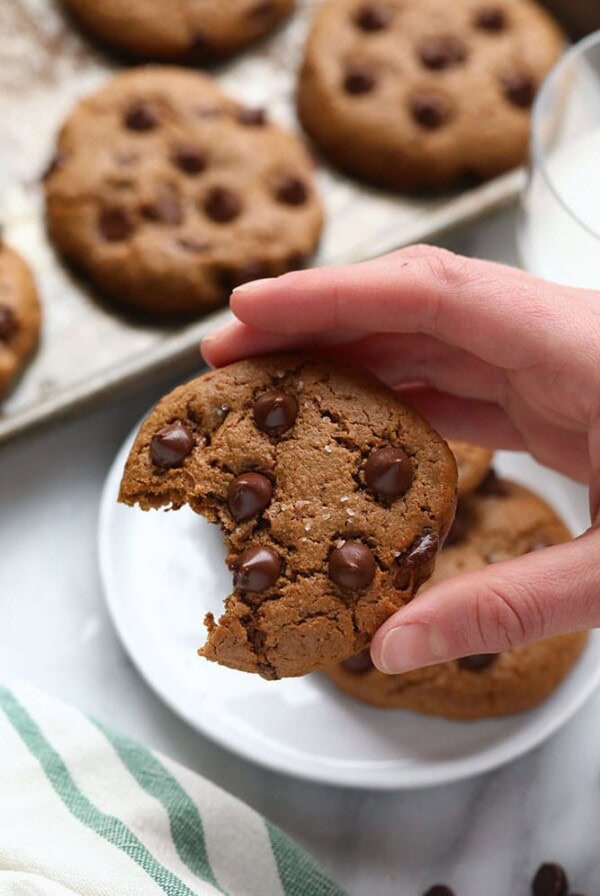 A person enjoying a bite of a paleo cashew butter cookie.