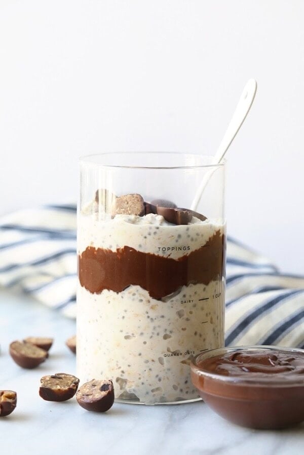 a glass of overnight chocolate oatmeal with a spoon and chocolate chips.