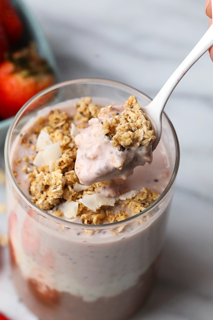 Neapolitan overnight oats served in a glass jar with a spoonful ready to eat.