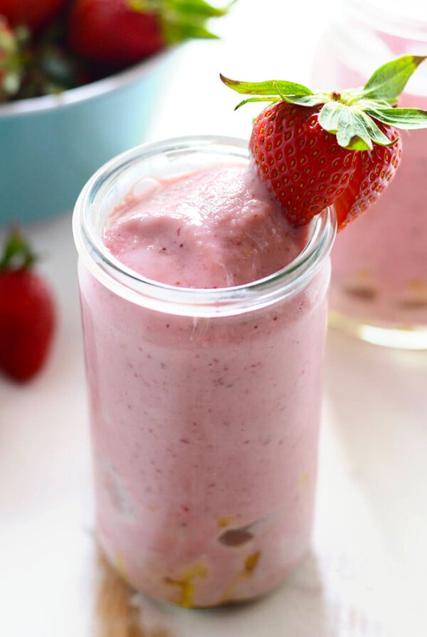 a pineapple upside-down drink in a jar with a strawberry on top.