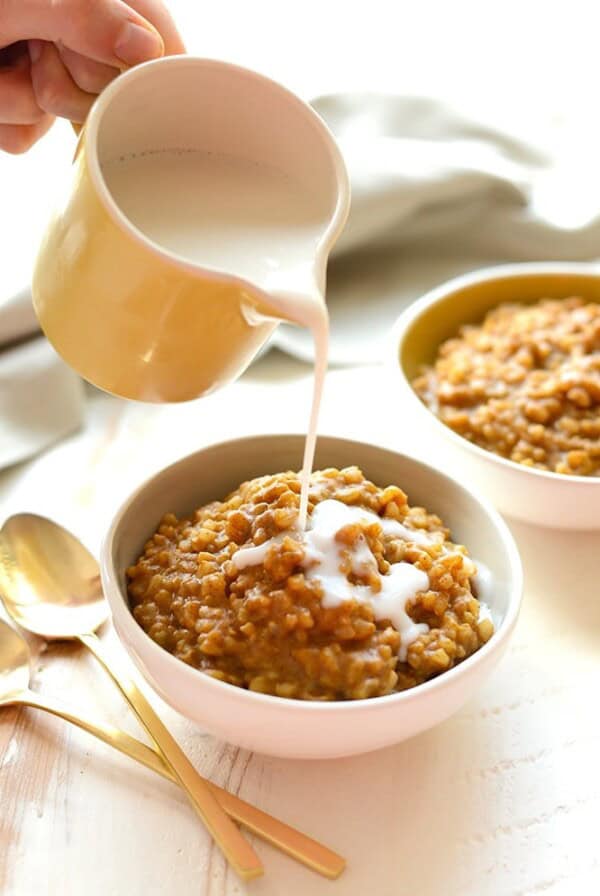 a person pouring milk into a bowl of oatmeal.