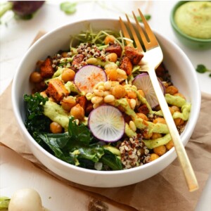 A buddha bowl recipe featuring quinoa and kale salad with a gold fork.