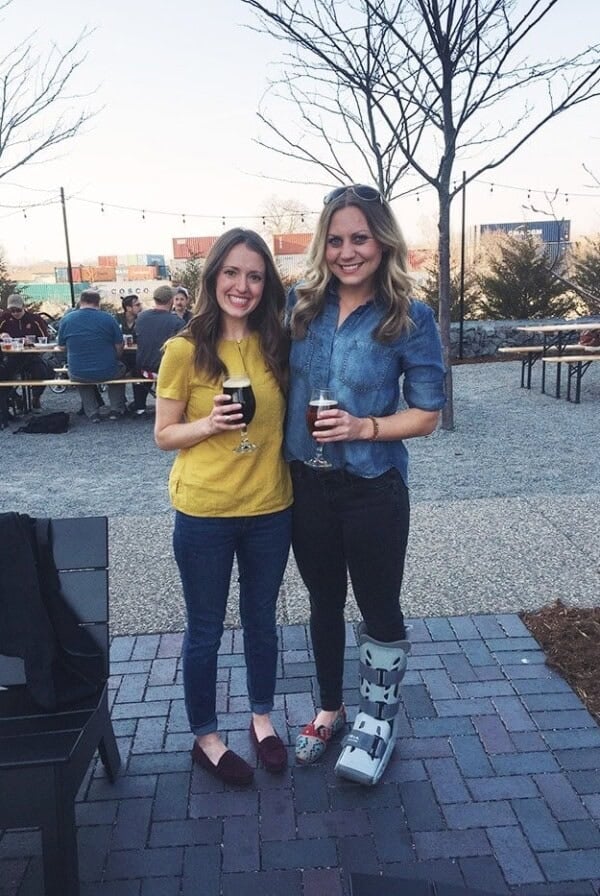 two women posing for a picture in front of a brick patio.