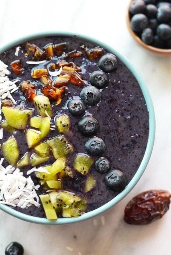 Blueberry and coconut smoothie bowl topped with kiwi and granola.