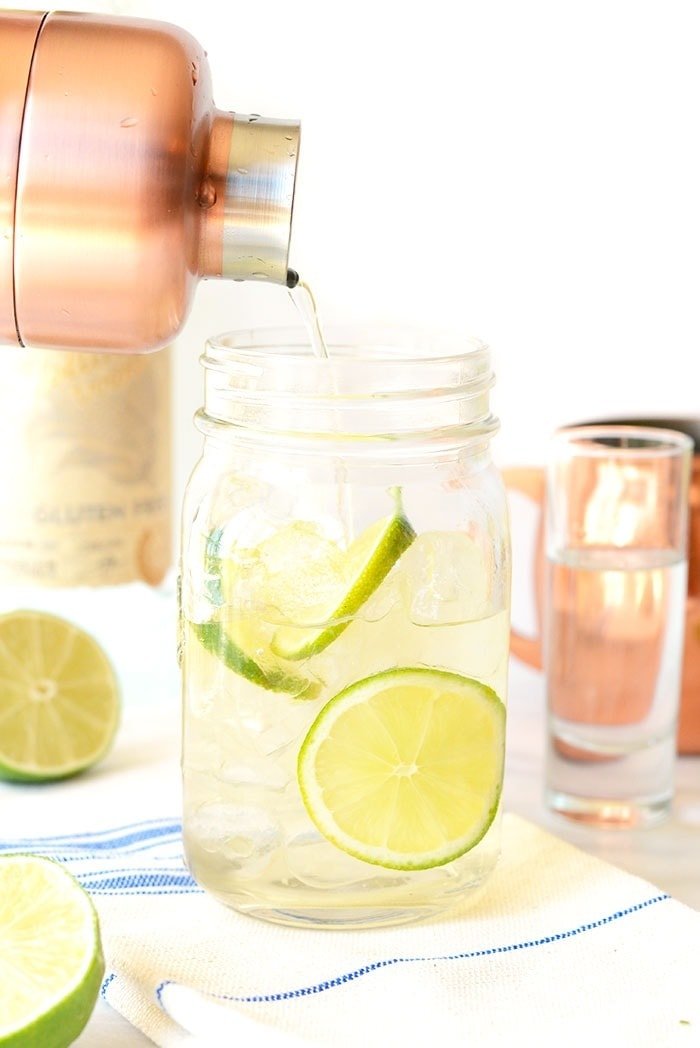 pouring Moscow mule from cocktail shaker into mason jar