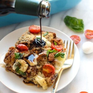 A person is pouring sauce on a Caprese Egg Bake.