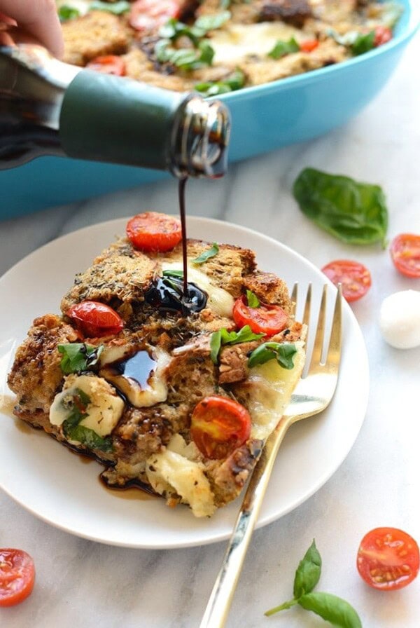 A person is pouring a sauce on a plate of bread for their Caprese Egg Bake.