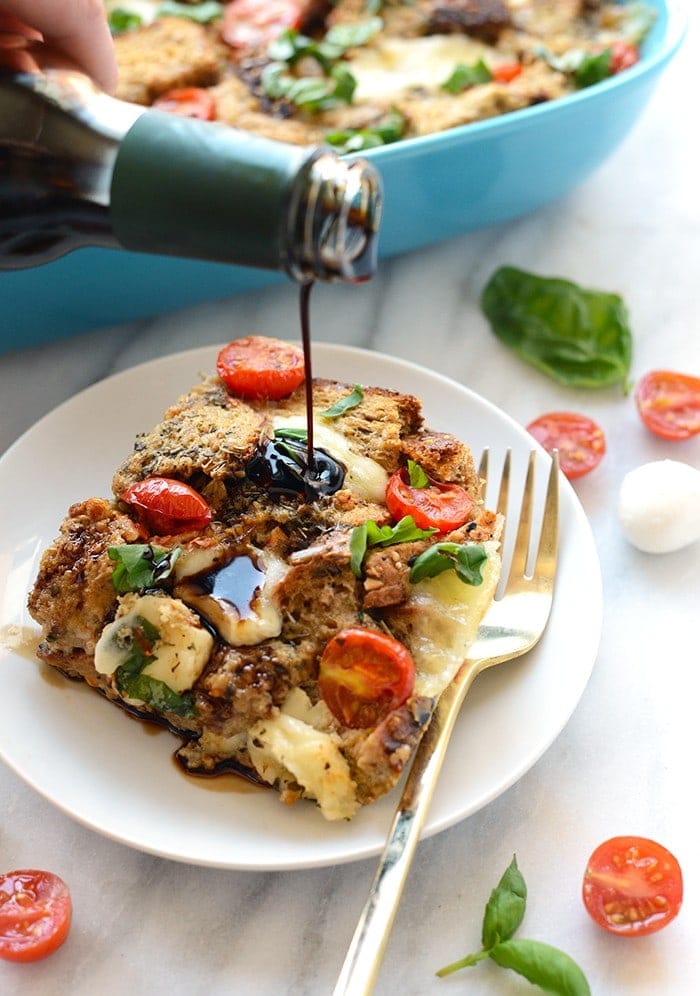 A person is pouring a sauce on a plate of bread for their Caprese Egg Bake.