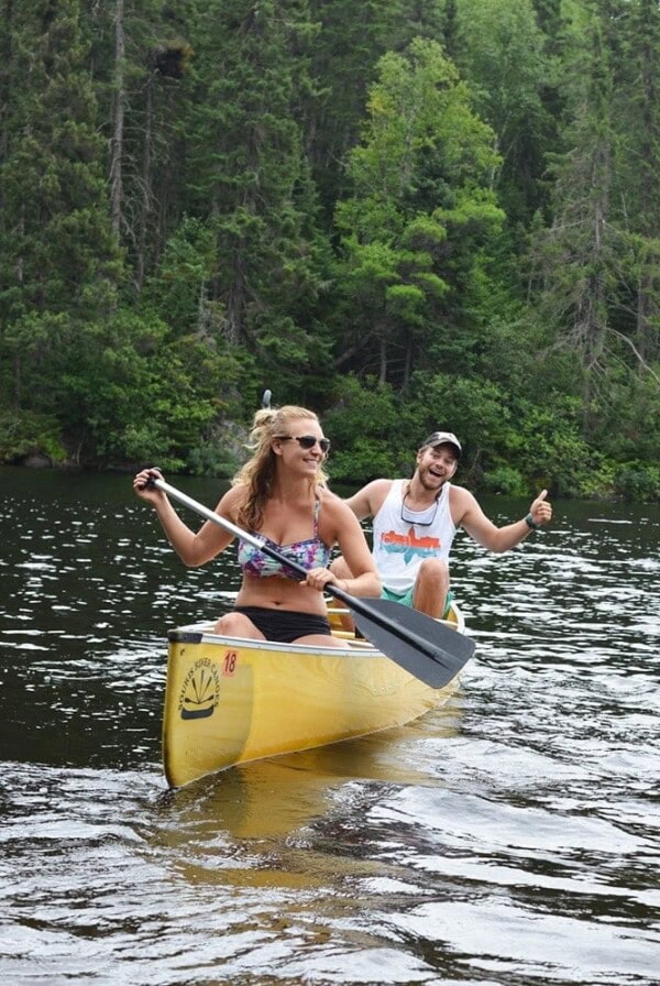 Two people paddling in a yellow canoe across The Boundary Waters.