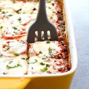 A person using a spatula to remove a Naked Lasagna Casserole from a baking dish.