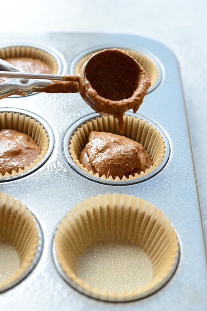 Chocolate pumpkin batter being scooped into a muffin tin