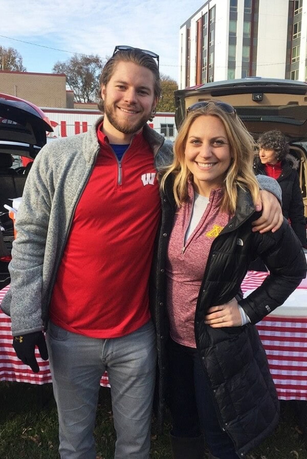 a man and woman posing for a picture in front of a picnic table.