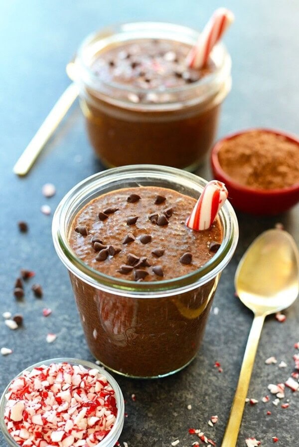 Two mugs of rich and indulgent chocolate peppermint chia seed pudding adorned with candy canes.