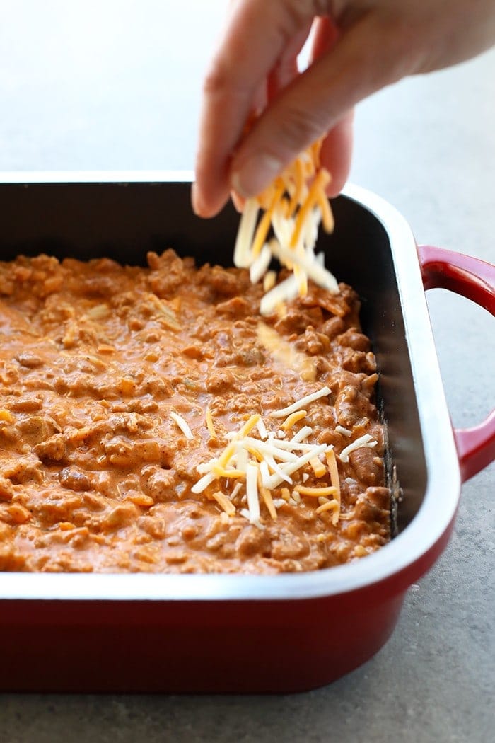 sprinkling cheese on bean dip