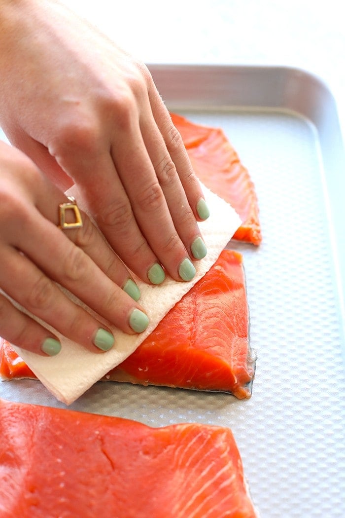 hands patting salmon fillets dry