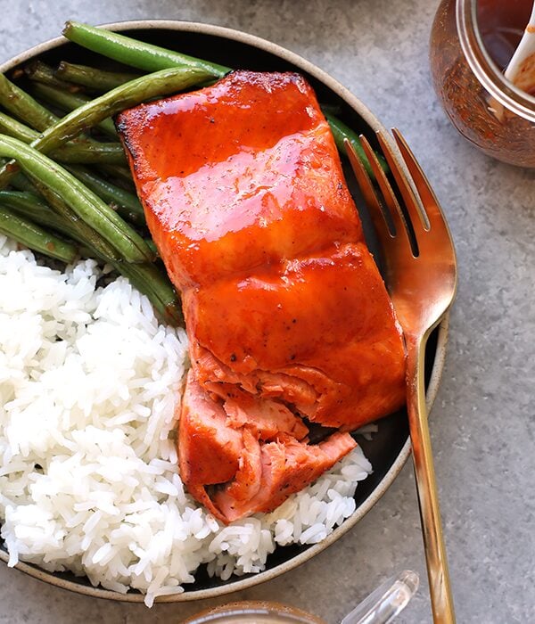 honey sriracha salmon on plate with rice and green beans and fork