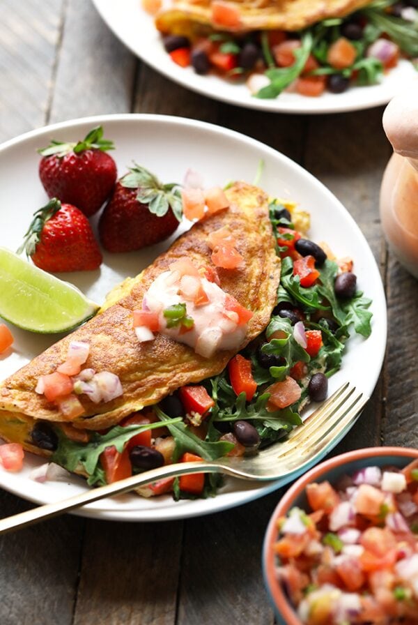 Two plates with veggie omelettes and salsa on them.