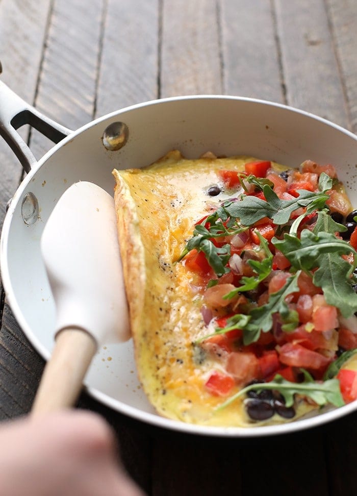 veggie omelette being folded over in skillet