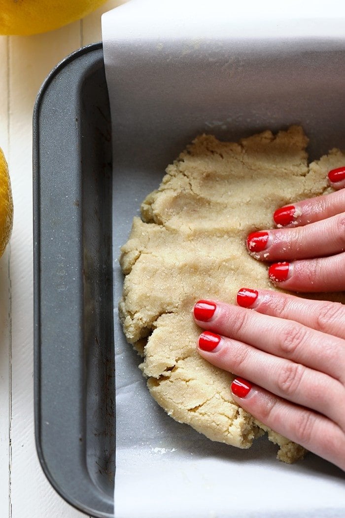 lemon bar crust being pressed in pan.