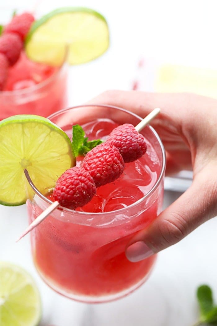 A hand holding a raspberry ginger mojito