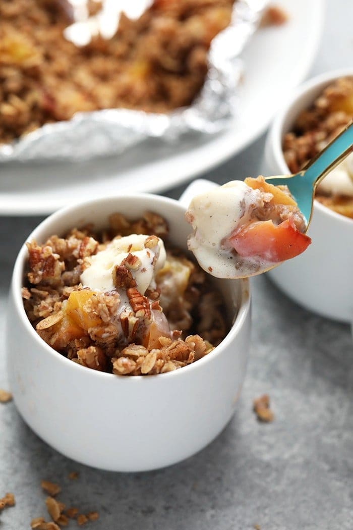 Peach crumble in coffee mug with spoon.