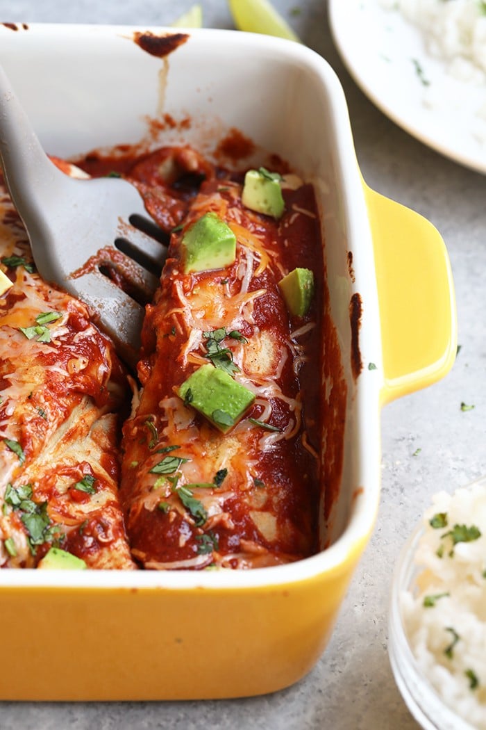 spatula dishing out a healthy enchilada from yellow baking dish