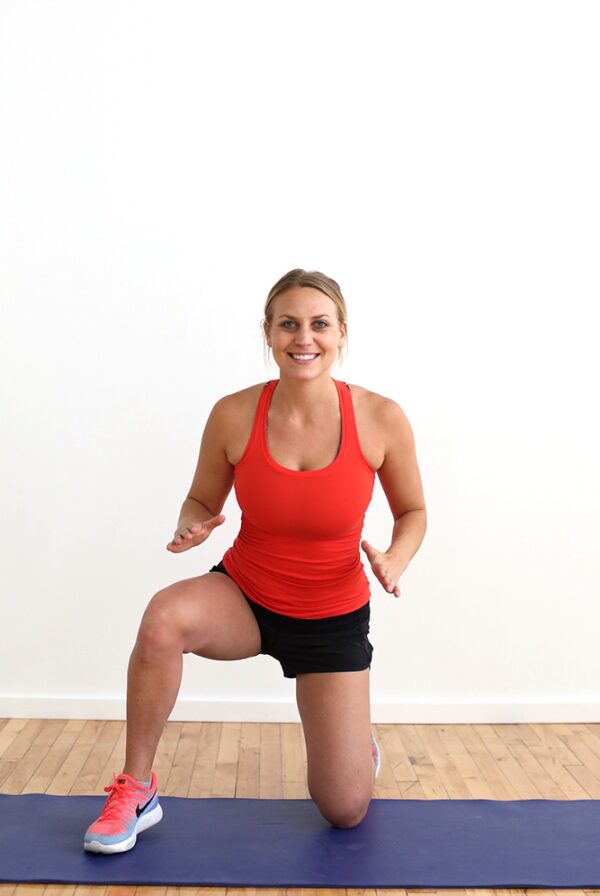 A woman engaging in a cardio and strength workout on a yoga mat.