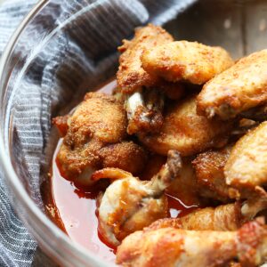 Baked chicken wings served in a bowl on a wooden table.