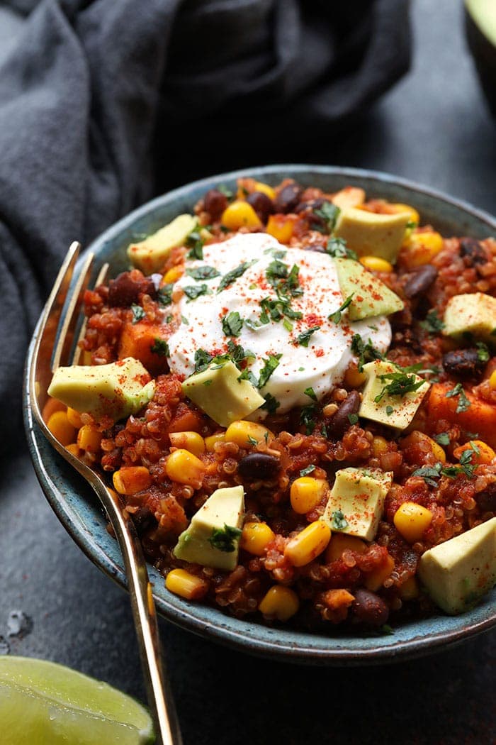 Bowl of Mexican quinoa with yogurt, paprika, cilantro, and avocado on top