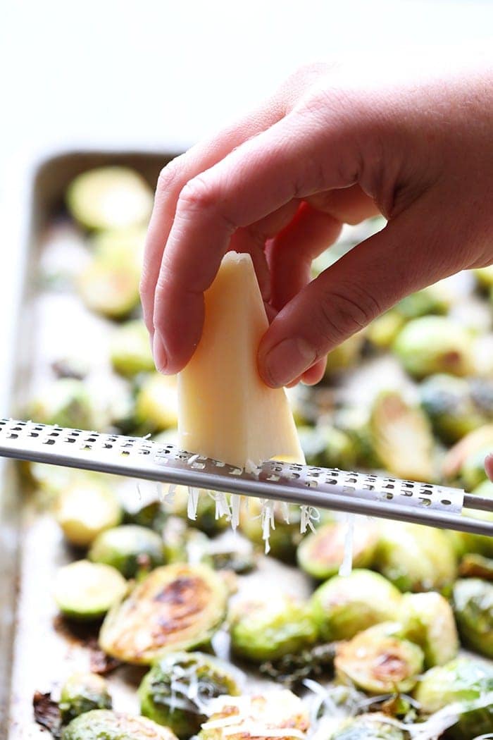 grating parmesan cheese onto brussel sprouts