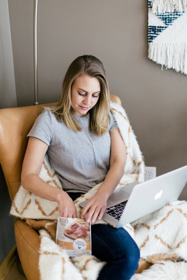 A woman at Fit Foodie HQ sitting in a chair, working on her laptop.