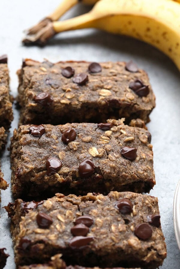 chocolate banana oat bars on a plate with bananas.